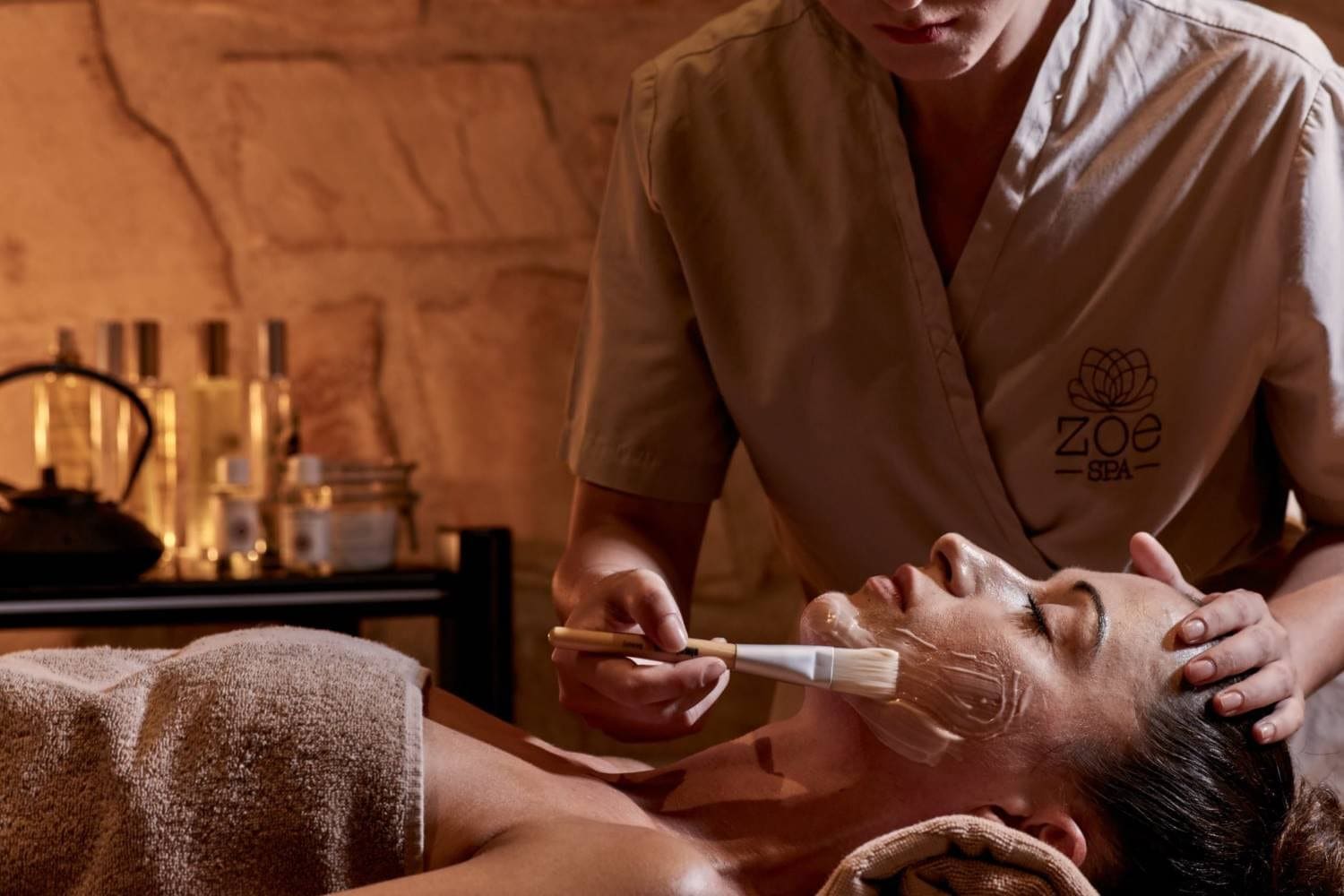 Spa therapist applying a facial mask with a brush at Zoe Spa Mykonos